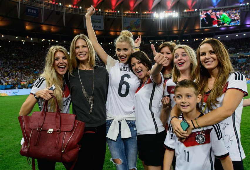 Wags, from left, Lisa Rossenbach, Sarah Brandner, Lena Gercke, Kathrin Glich, Lisa Wesseler and Sylwia Klose and her son invade the pitch to help their men celebrate victory